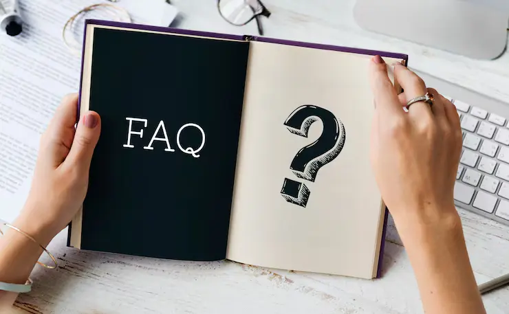 Hands holding an open notebook with FAQ and a question mark on its pages
