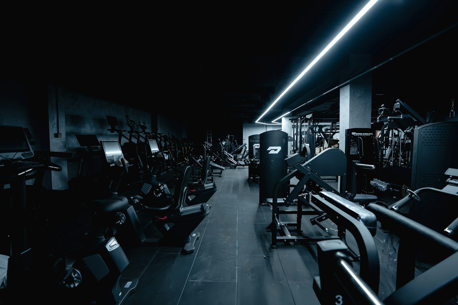 Rows of cardio machines under blue accent lighting on a VOLT studio's cardio deck